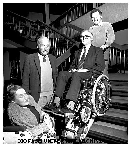 Stair-climbing wheelchair with designing engineer John Buckland (top), Safety Office Will Barker (in chair), Director of Health Services Dr John Green and Diploma of Education student Sue Shaw