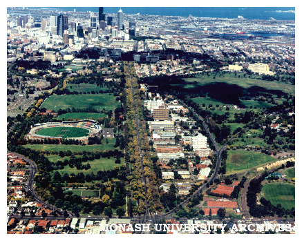 Aerial view of Victorian College of Pharmacy Parkville campus from north down Royal Parade with Optus Oval (Carlton Cricket Ground) on the left and Mebourne CBD in the distance.