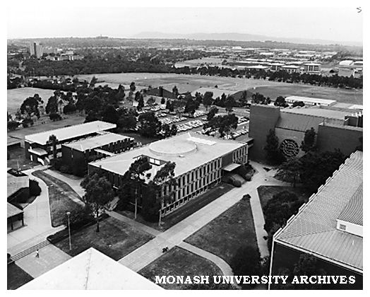 Raised view of University Offices, forum and Robert Blackwood Hall. Halls of Residence in background at right, with Police Academy and Mt. Dandenong on the horizon.