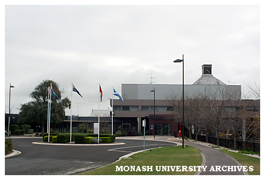 Flags at Eva West Circle with Building 1W in background, Gippsland campus