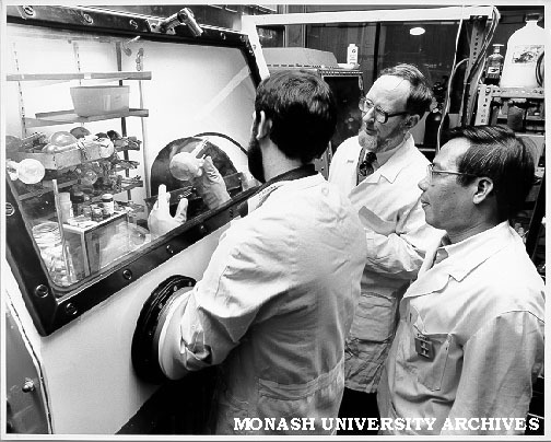 Student Dallas Wilkinson handling rare earth compound inside dry box, watched by Dr Glen Deacon (centre) and Dr Tran Tuong