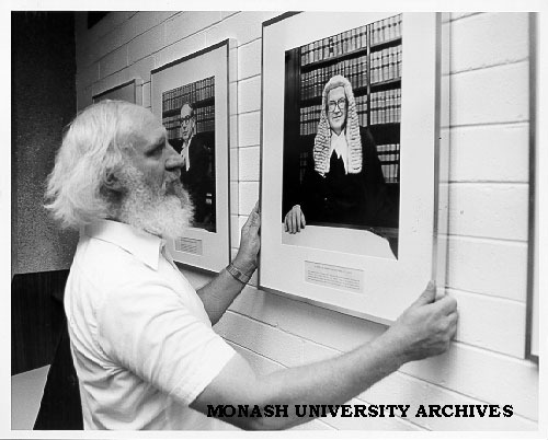 Senior lecturer Peter Balmford hanging portrait of Chief Justice Sir Harry Gibbs in Law library portrait gallery