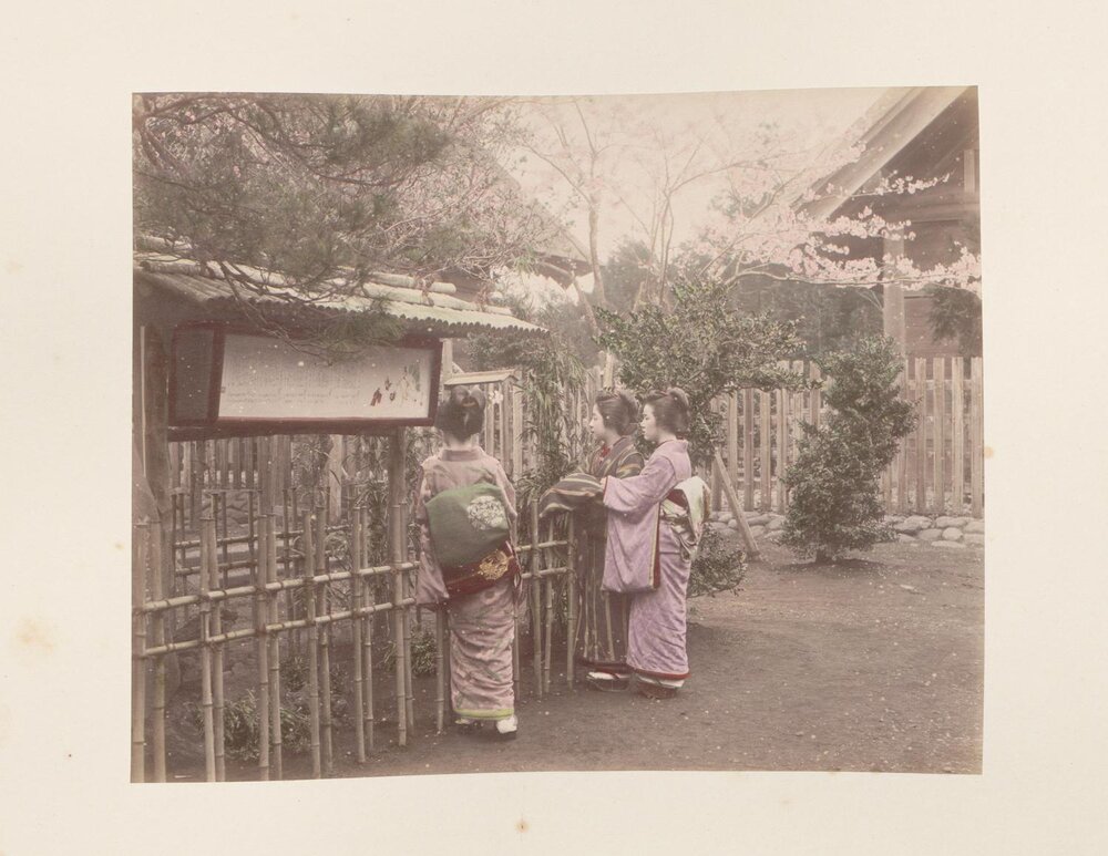 Three women reading sign in a garden
