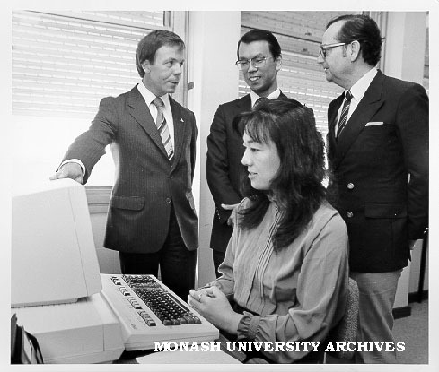 Visitor Miss Shigeko Nakamura using Epson QC 10 microcomputer with English and Japanese keyboard, watching from left: Mr Dan Price and Mr Shuzo Isoda from Epson Australia, and Professor Jiri Neustupny