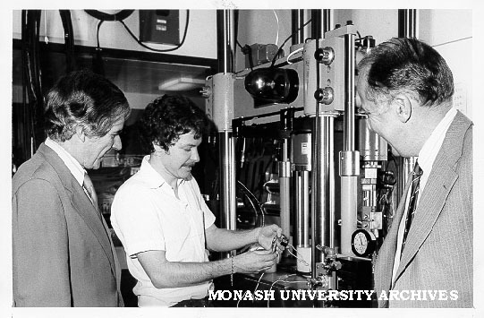 Vice-Chancellor Professor Ray Martin (left) watching student Russell Coade fatigue cracking sample of aluminium casting alloy. Professor Ian Polmear looking on