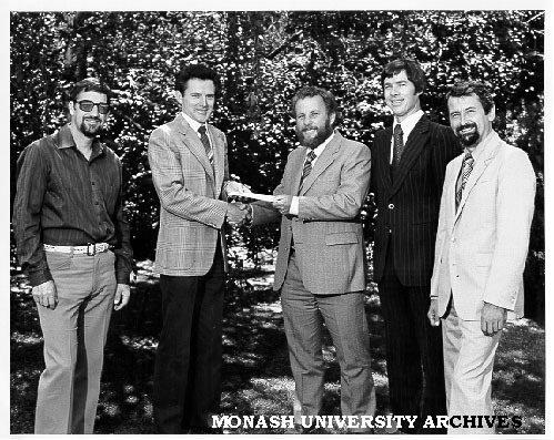 Dr Robin Alfredson (left) receiving AMIRA contract from Mr John Davidson. Looking on (from left) Mr Bruce Kuhnell, Dr David Nairn, and Mr Jacek Stecki