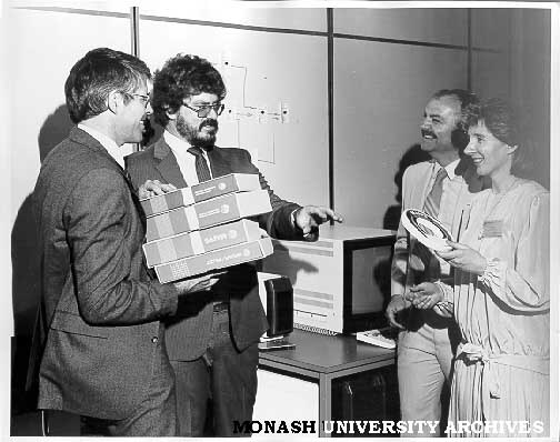 Handover of MONET software to Racal Electronics, Dr Cliff Bellamy (left), Mr Robert Morgan, Mr Roland Horat and Mrs Gail Morgan
