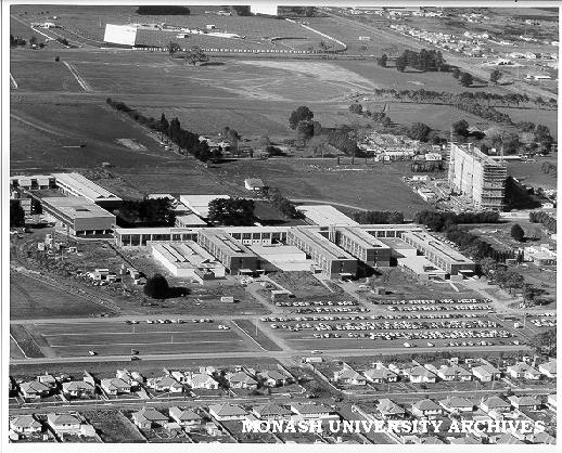 Aerial view of campus buildings, July 1962, from west, with drive-in theatre in background