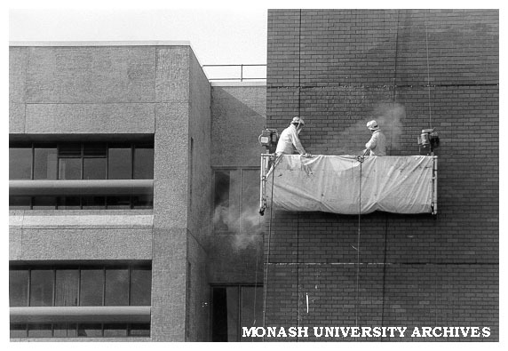 Building department staff cleaning wall of C block