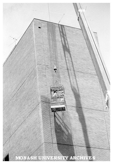 Building department staff cleaning wall of C block