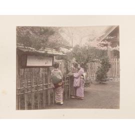 Three women reading sign in a garden
