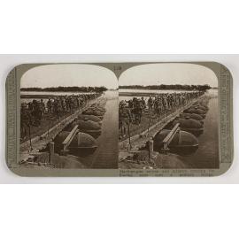 Machine-gun section and infantry crossing the flooded river over a pontoon bridge