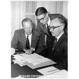 Senior administrators Mr F. H. Johnson (Comptroller)(left), Mr J. D. Butchart (Academic Registrar) and Dr Louis Matheson (Vice-Chancellor) examining agenda for first Professorial Board meeting