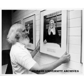 Senior lecturer Peter Balmford hanging portrait of Chief Justice Sir Harry Gibbs in Law library portrait gallery