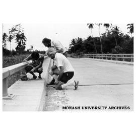 Geography students positioning traffic counter on Angabunga River bridge, Mr Stuart Hoverman, Father Michael Kennedy and Tony Simonelli