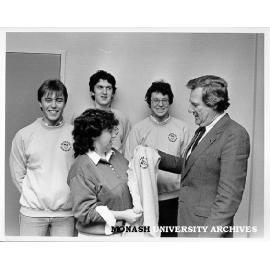Vice-Chancellor Professor Mal Logan presenting University Challenge team with Monash windcheaters, Trish Byron (front) watched by Brett Maxfield, Nick Laffey and Warren Batchelor