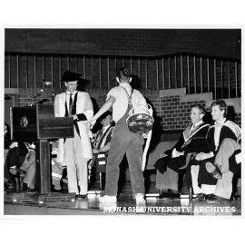 Student carrying out exorcism at opening of Orientation with Professor Alan Henry (standing), Graeme Sweeney and chairman of MAS Steve Hurd