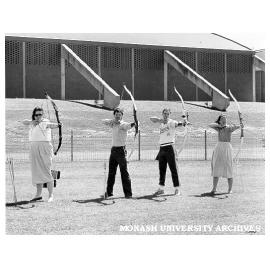 Archery Club members Natalie Tampion, Nick Hatzipantelis, David Maccora [and ?], practising on oval behind Sports and Recreation Centre