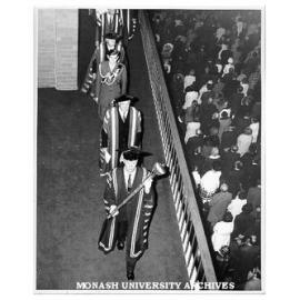 Academic procession leaving Robert Blackwood Hall after opening ceremony led by Comptroller Mr F. H. Johnson bearing Mace