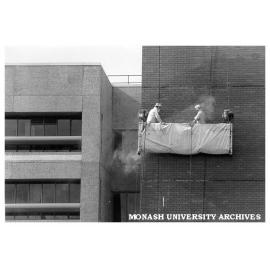 Building department staff cleaning wall of C block