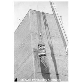 Building department staff cleaning wall of C block