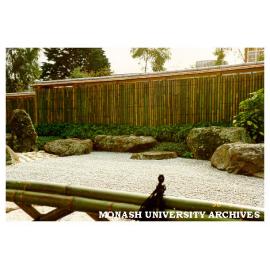 Japanese Garden with Kenninji style bamboo fence with a continuos roof topped in cedar bark with the stone (sekitei) garden in the foreground