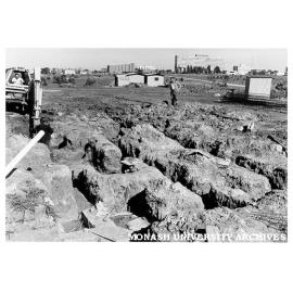Foundations for Roberts [?] Hall with university buildings in background