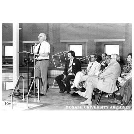 Doug Ellis, Sports & Recreation Association director, speaking at the opening of the swimming pool. Professor Ray Martin (seated middle front row)