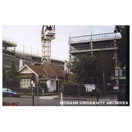 Construction of H building on Caulfield campus with house in foreground.