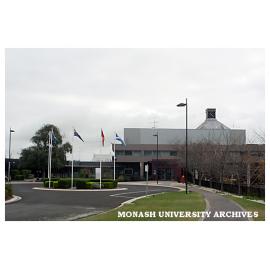 Flags at Eva West Circle with Building 1W in background, Gippsland campus