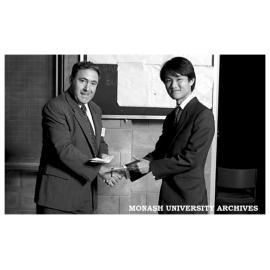 Lim Hock Gin (right) receiving the Digital Equipment prize for the best project in digital electronics or computer engineering from Mr John Baker.